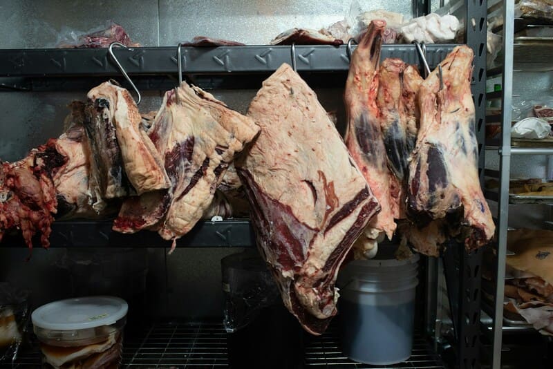 cortes de carne colgando de ganchos