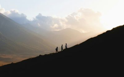 siluetas de tres personas subiendo una montaña