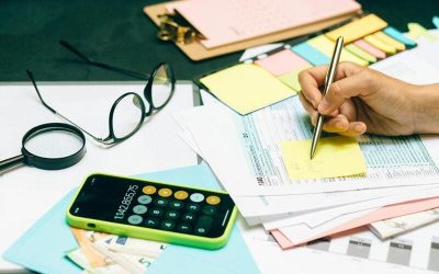Claves de la reforma impositiva- Mayor tranquilidad y menos trabas para el contribuyente Escritorio con papeles, calculadora, anteojos y mano con birome